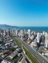 Aerial of road with cars, urban buildings by Meia Praia beach in Itapema City in Brazil