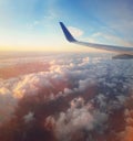 Aerial scene of a plane flight above the sunset colorful fluffy clouds. Airplane wing as seen through the window. Fly to the sky Royalty Free Stock Photo