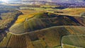 Aerial shot above a cultivated farmland and a village in the distance on a sunny day