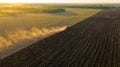 Aerial shot of agricultural field with tractor pulling a disc harrow over agricultural field, farmland Royalty Free Stock Photo