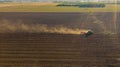 Aerial shot of agricultural field with tractor pulling a disc harrow over agricultural field, farmland