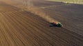 Aerial shot of agricultural field with tractor pulling a disc harrow over agricultural field, farmland