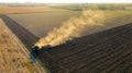 Aerial shot of agricultural field with tractor pulling a disc harrow over agricultural field, farmland