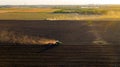 Aerial shot of agricultural field with tractor pulling a disc harrow over agricultural field, farmland