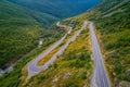 Aerial shot of an asphalt road on a green mountain near the river Royalty Free Stock Photo