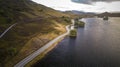 Aerial shot of an asphalt road on a mountain near the lake Royalty Free Stock Photo