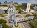 aerial shot of the Atlanta Olympic Cauldron Tower surrounded by lush green trees, cars driving on the street, skyscrapers