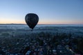 aerial shot of balloon ascending over a sleepy town at dawn