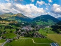 Aerial shot of beautiful alpine landscape with town, hills and deep valleys. Picturesque golden hour in mountains Royalty Free Stock Photo