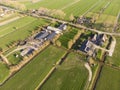 Aerial Shot of a beautiful Farm in The Netherlands surrounded with Bright green Fields in an evening hour