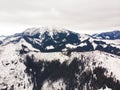 Aerial shot of beautiful winter scenery. Tranquil mountains' peeks covered with snow and dark-grey trees.