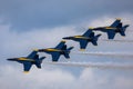 Aerial shot of the Blue Angels formation in a row performing an air show before the clouds Royalty Free Stock Photo