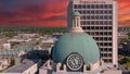 aerial shot of the blue clock tower on top of the Bibb County Courthouse surrounded hotels, office buildings and lush green trees