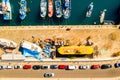 Aerial shot of boats tied to the dock side by side with cars parked on the road Royalty Free Stock Photo