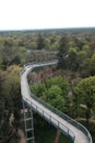 Aerial shot of a bridge curving over a lush forest landscape.