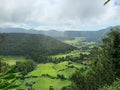 Aerial shot of Caldeira do Alferes hill surrounded by green fields and trees in Azores, Portugal Royalty Free Stock Photo