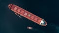 Aerial shot of a cargo ship approaching port with help of towing ship