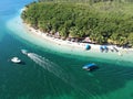 Aerial shot of an exotic beach resort with tiki huts and tourist boats