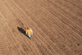 Aerial shot of female farmer walking through corn sprout field and examining crops. Farm worker wearing trucker`s hat and jeans o