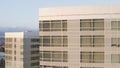 An aerial shot of a flyby of a building with glass windows in which the sun is reflected. Building in an urban