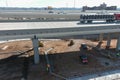 A aerial shot of a freeway with cars and semi trucks driving on the highway with construction workers working underneath