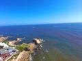 An aerial shot of a gorgeous summer landscape at the beach with blue ocean water and waves crashing into the large rocks Royalty Free Stock Photo