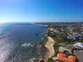 An aerial shot of a gorgeous summer landscape at the beach with blue ocean water and waves crashing into the large rocks Royalty Free Stock Photo