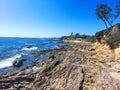 An aerial shot of a gorgeous summer landscape at the beach with blue ocean water and waves crashing into the large rocks Royalty Free Stock Photo