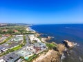 An aerial shot of a gorgeous summer landscape at the beach with blue ocean water and waves crashing into the large rocks Royalty Free Stock Photo