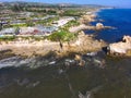 An aerial shot of a gorgeous summer landscape at the beach with blue ocean water and waves crashing into the large rocks Royalty Free Stock Photo