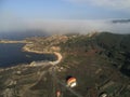 Aerial shot of grassy fields near the sea under a foggy sky in Galicia, Spain Royalty Free Stock Photo