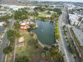 Aerial shot of the green lake, lush green trees, grass and plants at Lincoln Park with a train on the railroad tracks and cars