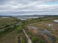 Aerial shot of green plants in a wetland and a road under the clouded sky