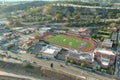 Aerial shot of hillside covered with lush green trees in front of Dodgers Stadium surrounded by buildings, cars, streets