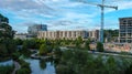 An aerial shot of the lake in the park and the cityscape with green trees around the lake and tower cranes and buildings