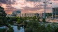 An aerial shot of the lake in the park and the cityscape with green trees around the lake and tower cranes and buildings