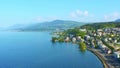 Aerial shot of Lake Zurich with town on shore, hazy mountains in distance