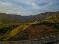 An aerial shot of the majestic mountain ranges with homes along the coastline of California, freeways with cars and blue sky