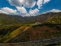 An aerial shot of the majestic mountain ranges with homes along the coastline of California, freeways with cars and blue sky