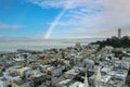 aerial shot of the ocean and streets lined with apartments, lush green trees and Coit Tower with blue sky, clouds and a rainbow Royalty Free Stock Photo