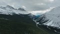 Aerial shot of ocky mountains covered with forestand the road in Alberta, Canada