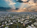 Aerial shot of the office buildings, apartments and shops in the city skyline surrounded by lush green trees, roads and cars on