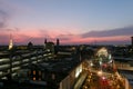 Aerial shot of office buildings and tower cranes in the city skyline with lights and cars driving along the street at sunset Royalty Free Stock Photo