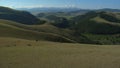 Aerial shot of open rangeland with forest and mountains