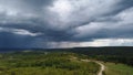 Aerial shot of a path amid the green trees in the background of a mountain under the cloudy sky Royalty Free Stock Photo