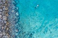 Aerial shot of a person swimming in the sea surrounded by rocks in Protaras, Cyprus