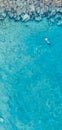 Aerial shot of a person swimming in the sea surrounded by rocks in Protaras, Cyprus