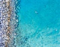 Aerial shot of a person swimming in the sea surrounded by rocks in Protaras, Cyprus