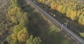 Aerial shot of railroad between autumn trees in forest in october Royalty Free Stock Photo