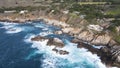 Aerial shot of a rocky shoreline with pounding waves crashing against the large rocks. Royalty Free Stock Photo